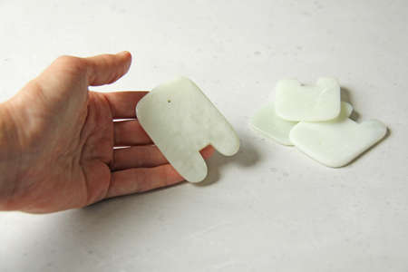 Massage of face and body. Female hand holds gouacha in its palm, made from natural stone mineral White jade. Therapeutic healing massage for beauty and youth of face, body. Copy space for your text.の写真素材