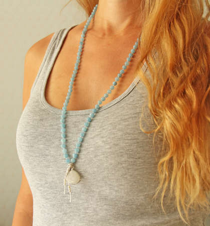 Rosary mala 108 beads from natural stones Aquamarine are worn on a girl in a gray shirt. Author's jewelry from natural stones, Buddhism, matra, prayer, rosary from stones for prayer and beauty.の写真素材