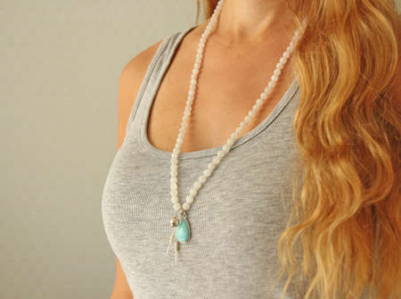 Rosary mala 108 beads from natural stones Moonstone are worn on a girl in a gray shirt. Author's jewelry from natural stones, Buddhism, matra, prayer, rosary from stones for prayer and beauty.の写真素材