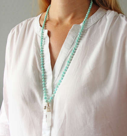 Rosary mala 108 beads from natural stones mint amazonite are worn on a girl in a white shirt. Author's jewelry from natural stones, Buddhism, matra, prayer, rosary from stones for prayer and beauty.の写真素材