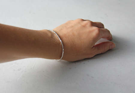 Silver bracelet. Bracelet on hand from Silver. Handmade jewelry. Handmade bracelets on light modern background.の写真素材