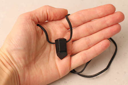 A pendant made of natural stone Morion quartz silver lies on a woman's hand. Author's jewelry from natural stones. Designer jewelry. On a light modern background. Natural minerals.の写真素材