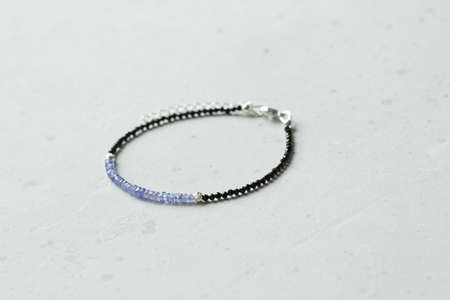 Tanzanite black spinel bracelet. Bracelet made of stones on hand from natural stone Tanzanite, spinel. Bracelet made of natural stones. Handmade jewelry. Handmade bracelets on light modern background.の写真素材