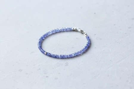 Tanzanite bracelet. Bracelet made of stones on hand from natural stone Tanzanite. Bracelet made of natural stones. Handmade jewelry. Handmade bracelets on light modern background.の写真素材