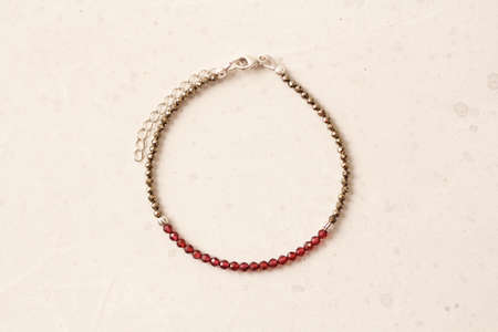 Pyrite, Garnet bracelet. A bracelet made of stones on a hand from natural stone Pyrite, Garnet. Bracelet made of natural stones. Handmade jewelry. Handmade bracelets on light modern background.の写真素材
