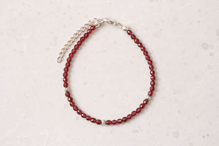 Garnet bracelet. Bracelet made of stones on hand from natural stone Garnet. Bracelet made of natural stones pomegranate. Handmade jewelry. Handmade bracelets on light modern background.の写真素材