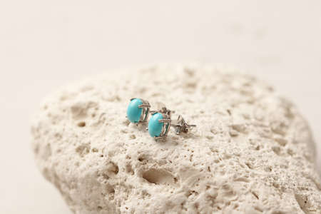 Stud earrings made of natural turquoise sleeping beauty. Designer earrings from natural turquoise stones. Women's jewelry on a light background and stone. Author's modern jewelry.の写真素材