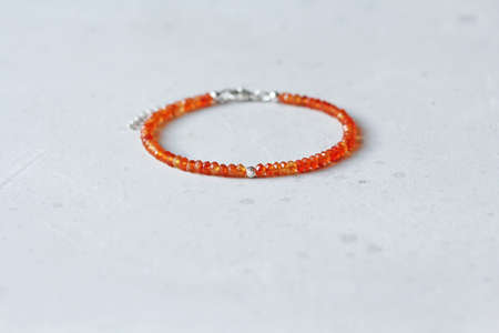 Carnelian bracelet. Bracelet made of stones on hand from natural stone Carnelian. Bracelet made of natural stones. Handmade jewelry. Handmade bracelets on light modern background.の写真素材
