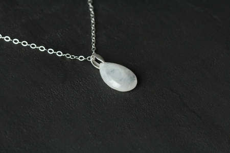 Bright delicate multi-colored tourmaline, moonstone bracelet rests on black modern concrete background. Bracelet made of stones on hand. Handmade bracelets on black modern background. LGBT bracelet.の写真素材