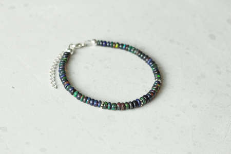 Bright delicate multi-colored tourmaline, moonstone bracelet rests on black modern concrete background. Bracelet made of stones on hand. Handmade bracelets on black modern background. LGBT bracelet.の写真素材