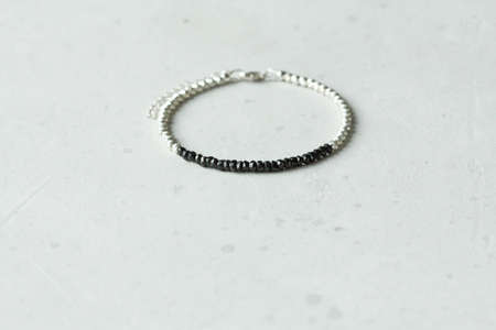 Bright delicate multi-colored tourmaline, moonstone bracelet rests on black modern concrete background. Bracelet made of stones on hand. Handmade bracelets on black modern background. LGBT bracelet.の写真素材