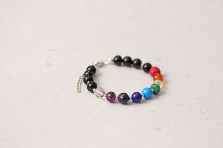 Bright delicate multi-colored tourmaline, moonstone bracelet rests on black modern concrete background. Bracelet made of stones on hand. Handmade bracelets on black modern background. LGBT bracelet.の写真素材