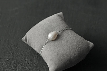 Bright delicate multi-colored tourmaline, moonstone bracelet rests on black modern concrete background. Bracelet made of stones on hand. Handmade bracelets on black modern background. LGBT bracelet.の写真素材