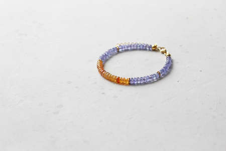 Bright multicolored bracelet. Ruby, coral, carnelian, citrine, emerald, apatite, amazonite, turquoise, lapis lazuli, tanzanite, black spinel. Handmade jewelry bracelets on light modern background.の写真素材