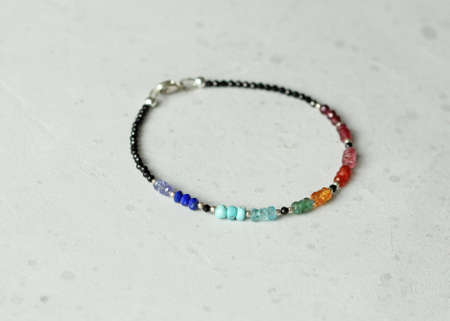 Bright multicolored bracelet. Ruby, coral, carnelian, citrine, emerald, apatite, amazonite, turquoise, lapis lazuli, tanzanite, black spinel. Handmade jewelry bracelets on light modern background.の写真素材