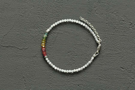 Bright delicate multi-colored tourmaline, moonstone bracelet rests on black modern concrete background. Bracelet made of stones on hand. Handmade bracelets on black modern background. LGBT bracelet.の写真素材