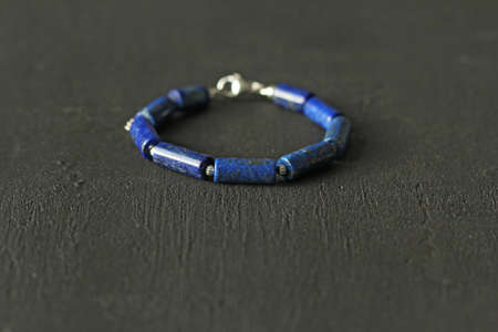 Blue natural lapis lazuli Bracelet made of natural stones lies on a black modern concrete...