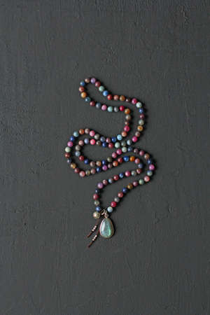 Rosary mala 108 beads from natural stones tourmaline lie on black modern background. Author's jewelry from natural stones, Buddhism, mantra, prayer, rosary from stones for prayer, beauty. Long beads.の写真素材