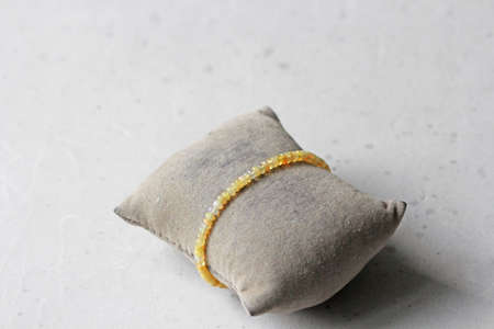 Fire opal, gilding bracelet. Bracelet made stones on hand from natural stone fire opal. Bracelet made of natural stones. Handmade jewelry. Bracelets on light modern background. On jewelry cushion.の写真素材