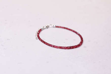 Ruby silver bracelet. Bracelet made of stones on hand from natural stone ruby. Bracelet made of natural stones. Handmade jewelry. Handmade bracelets on light modern background. Thin bracelet.の写真素材