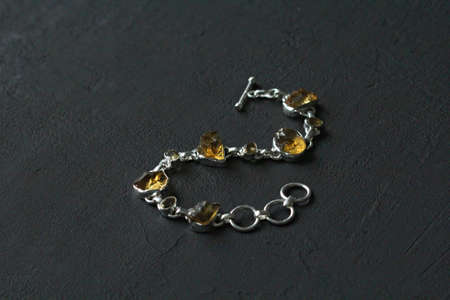 Citrine bracelet. Bracelet made of stones on hand from natural stone Citrine. Bracelet made of natural stones. Handmade jewelry. Handmade bracelets on black modern background. Stylish stone jewelry.の写真素材