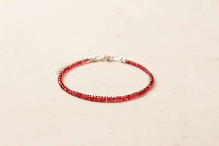 Ruby silver bracelet. Bracelet made of stones on hand from natural stone ruby. Bracelet made of natural stones. Handmade jewelry. Handmade bracelets on light modern background. Thin bracelet.の写真素材