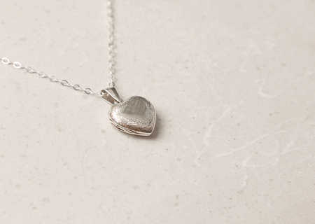 Medallion pendant in shape of heart made of silver on chain. Love, romance, beautiful romantic gift heart medallion pendant, jewelry on the girl. Heart-shaped medallion pendant, silver.の写真素材