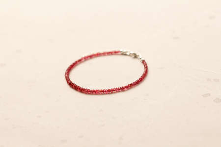 Ruby silver bracelet. Bracelet made of stones on hand from natural stone ruby. Bracelet made of natural stones. Handmade jewelry. Handmade bracelets on light modern background. Thin bracelet.の写真素材