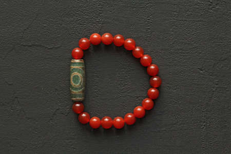 Carnelian stone Dzi bead 3 eyes bracelet. Bracelet made of stones on hand from natural Carnelian. Handmade jewelry bracelets on light background. Tibetan dzi beads 3. Buddhism, fulfillment of desires.の写真素材