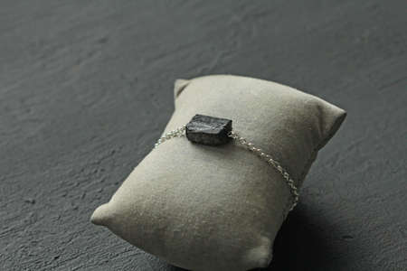 Black tourmaline, sherl bracelet on silver chain. Bracelet made of stones on hand from natural stone Black tourmaline on black concrete modern background. Magic jewelry, lithotherapy, stone therapy.の写真素材