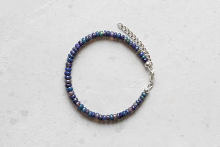 Black fire opal bracelet. Bracelet made of stones on hand from natural stone Black Fire opal. Bracelet made of natural stones. Handmade jewelry. Handmade bracelets on light modern background.の写真素材