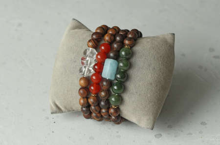 Bracelets made of natural pear wood and natural stones. Elastic bracelets. Author's jewelry handmade bracelets on a light modern concrete background. Rock crystal, carnelian, aquamarine, green jade.の写真素材