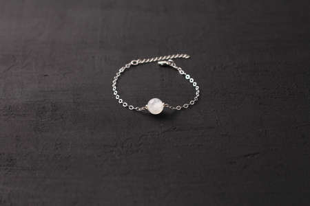 Moonstone, adularia bracelet. Bracelet made of stones on hand from natural stone Moonstone. Bracelet made of natural stones. Handmade jewelry bracelets on black modern background.の写真素材