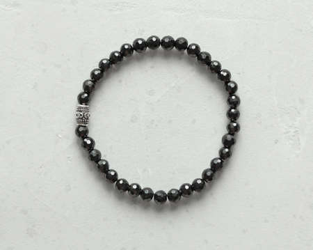 Black spinel, tourmaline bracelet. Bracelet made of stones on hand from natural stone Black spinel, tourmaline. Bracelet made of natural stones. Handmade jewelry bracelets on light modern background.の写真素材