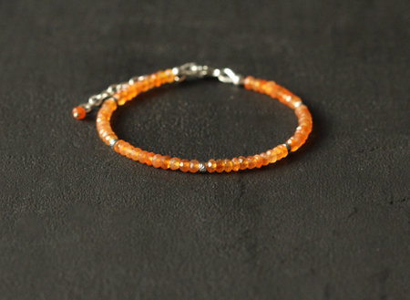 Natural Carnelian thin bracelet. Bracelet made of stones on hand from natural stone Carnelian. Bracelet made of natural stones. Handmade jewelry. Handmade bracelets on black modern background.の写真素材