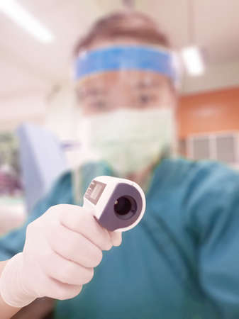 Selective focus of Infrared thermometer on blurred background. of asian woman doctor or nurse.の写真素材