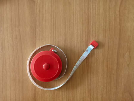 red circle measure tape with white line on wooden texture.