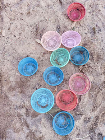 Many plastic basket disrupted on sand.