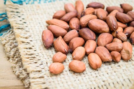 Raw peanuts or arachis on sack on wooden table
