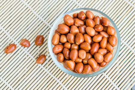 Roasted peanuts in glass cup put on the pad mat