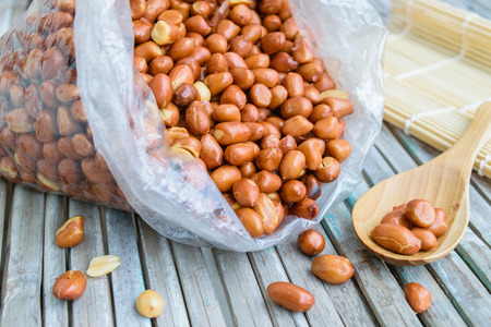 Roasted peanuts in plastic bag on wooden table