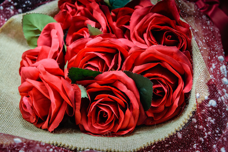 Bouquet of beautiful red roses wrapped into brown sack clothの写真素材