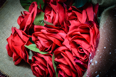 Bouquet of beautiful red roses wrapped into brown sack clothの写真素材