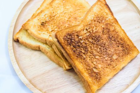 toasted bread on wooden plate isolated on white backgroundの写真素材