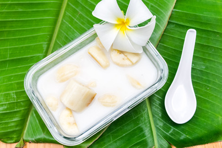Banana in coconut milk with flowers on banana leaf, Thai dessertの写真素材