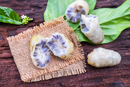 Noni fruit on sack on old wooden tableの写真素材