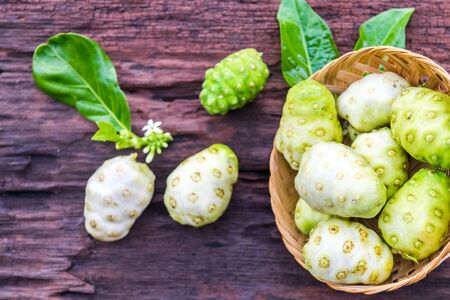 Noni fruit in basket on old wooden tableの写真素材