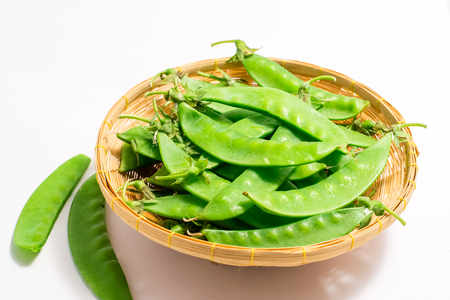 Snow peas in bamboo basket  on white backgroundの写真素材