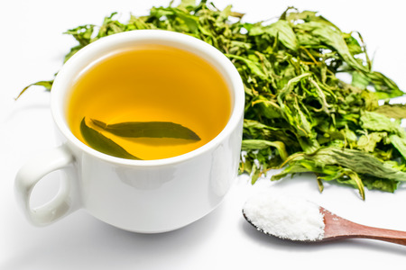 Dry stevia leaves with a white cup stevia infusion on white backgroundの写真素材