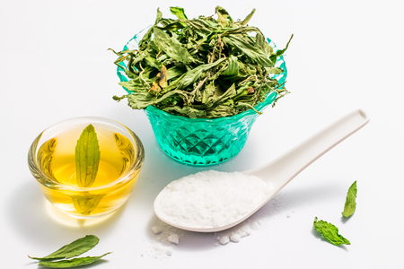 Dry stevia leaves in green glass on white backgroundの写真素材